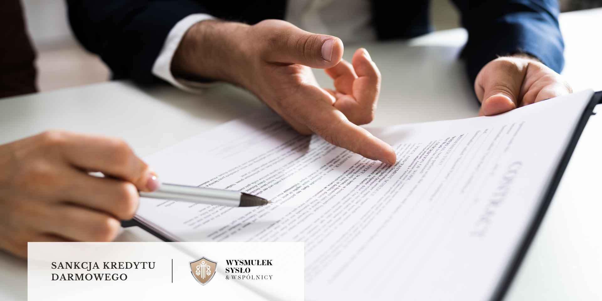 sankcja-kredytu-darmowego-obowiazek-informacyjny <br />
Zbliżenie na dokument umowy, przy którym dłoń mężczyzny wskazuje na konkretne zapisy, a dłoń kobiety trzyma długopis