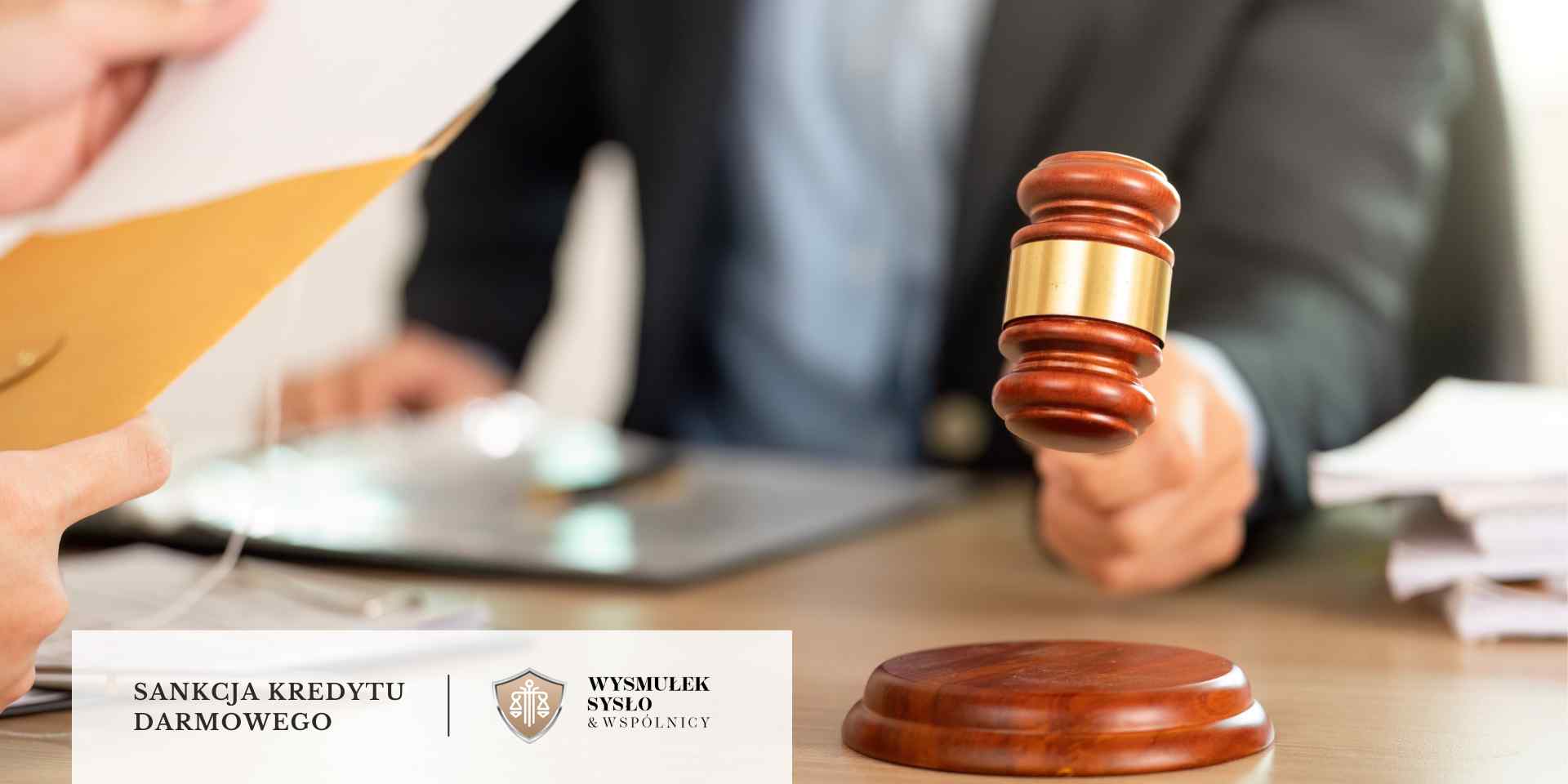 Dłoń trzyma brązową kopertę nad stołem, na którym widoczny jest prawnik w garniturze i uniesiony drewniany młotek sędziowski